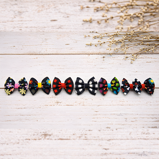 Row of colorful bow-shaped hair accessories on a light wooden surface with dried flowers.