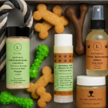 Assorted pet care products including natural deodorant, balms, and toys on a gray surface.